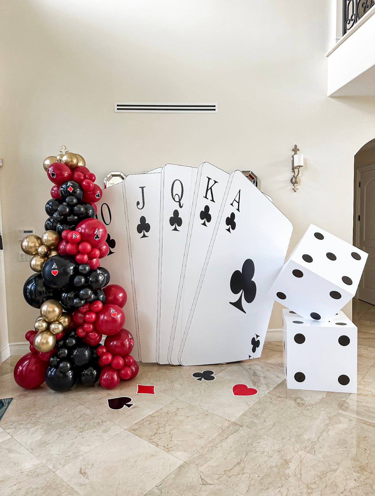 Casino-themed event display with giant cards, dice and black red gold balloons