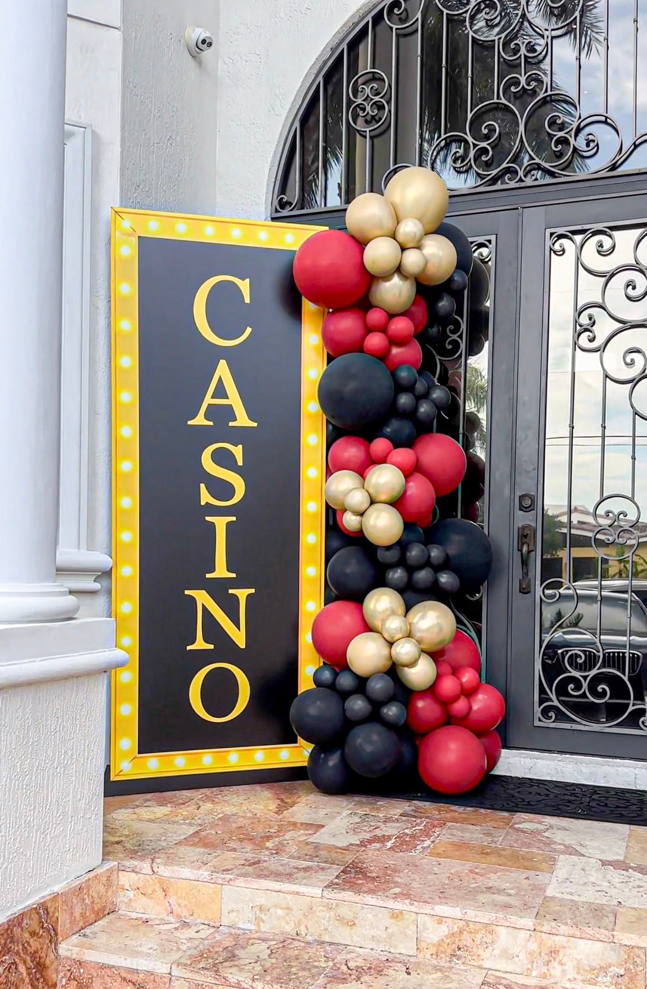 Casino night marquee sign with black, red and gold balloon column