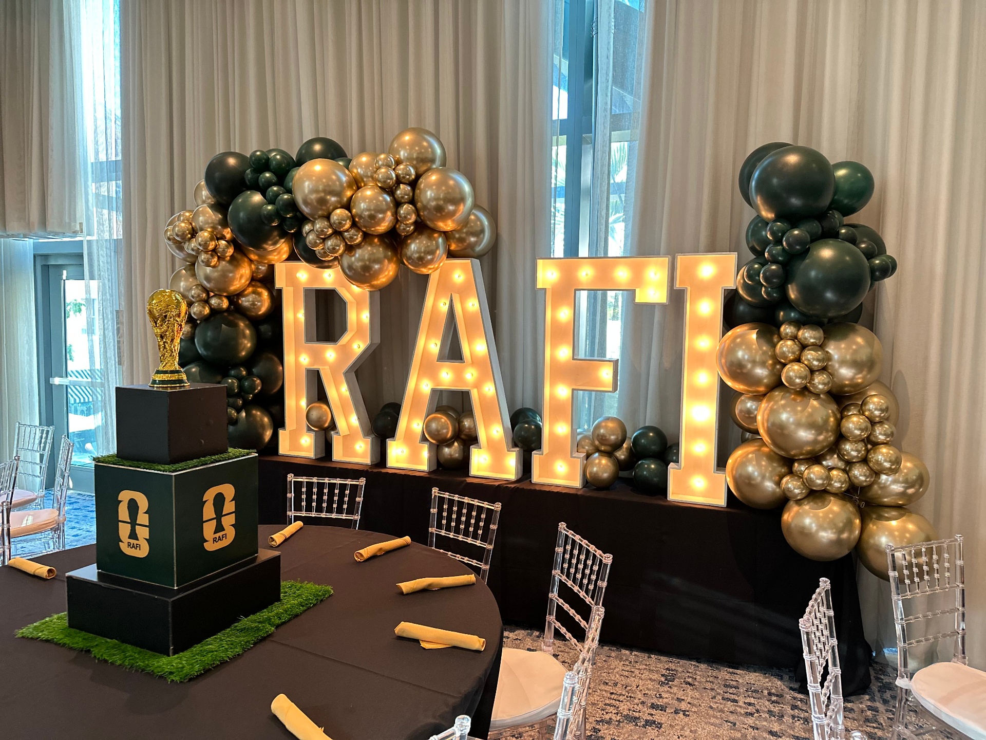 RAFI marquee letters with green and gold balloon garland
